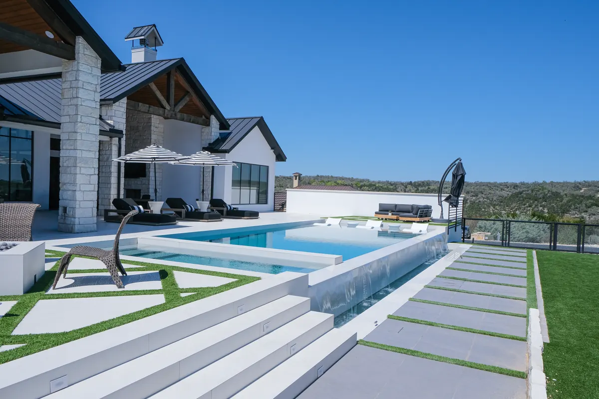 Ambia pool with an overflowing edge, white terraces and a view across the Texas hills